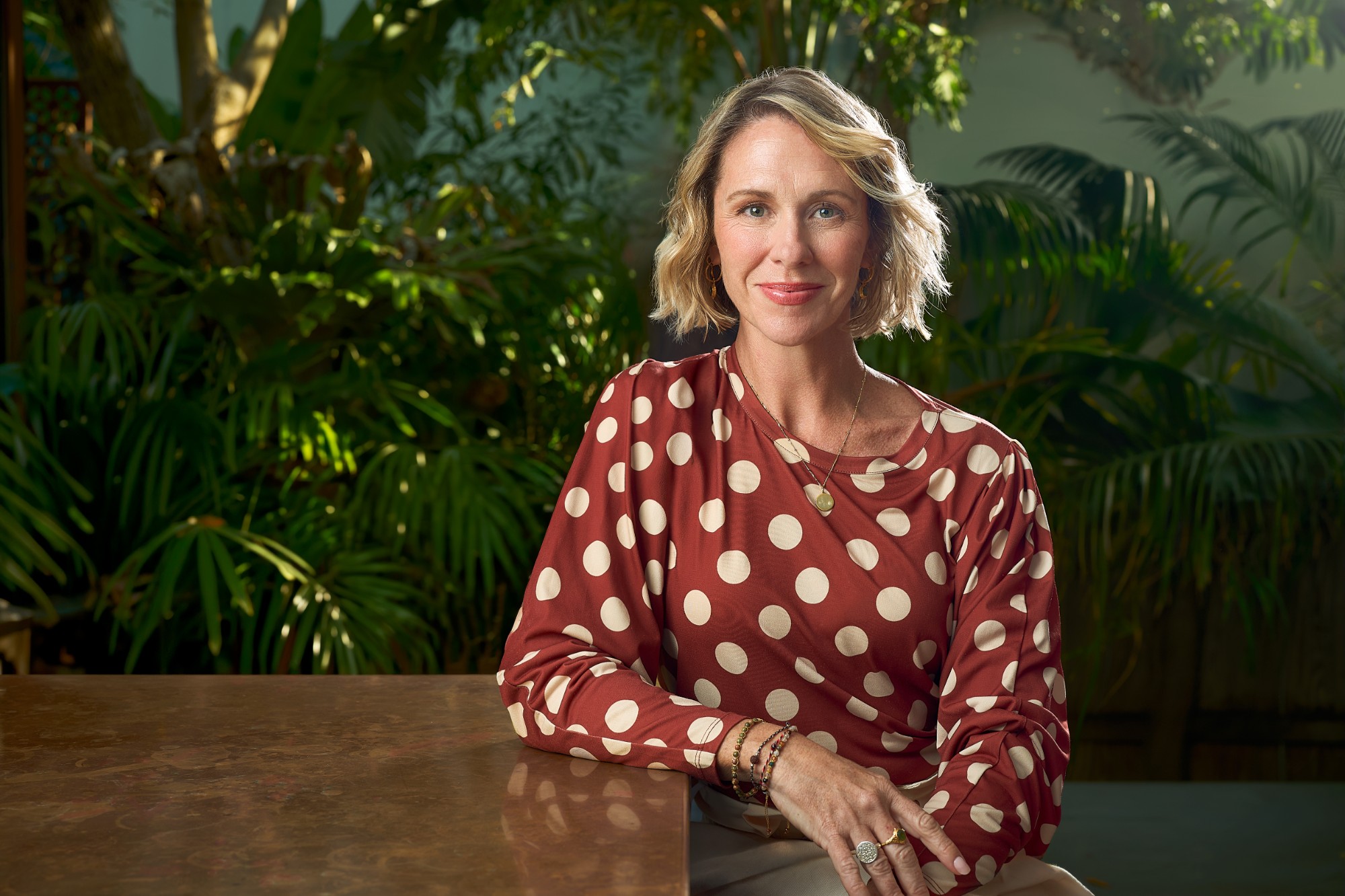 Kate Reardon seated at a table in a garden, smiling warmly